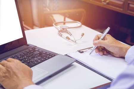 Doctor holding pen writing report Cancer Treatment Plan on desk with sunset light.Selective focusの写真素材