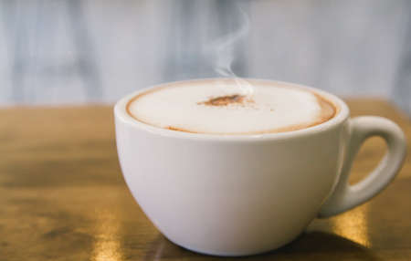 cup of hot coffee with foam and smoke on table in the morning. copyspace for your textの写真素材