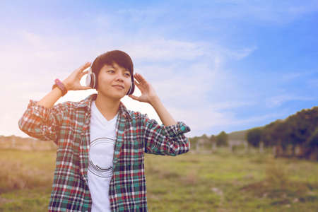 Teen are listening to music at close range with a light sunset background.の写真素材