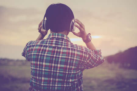 Teens are listening to music at close range with a light sunset background.の写真素材