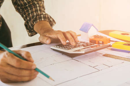 Concept architects,engineer holding pen pointing equipment architects On the desk with a blueprint in the office, Vintage, Sunset light.Selective Focusの写真素材