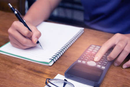 Asian young woman in blue shirt holding pen working ,Calculate tax lead to liquidation, With Sunset...