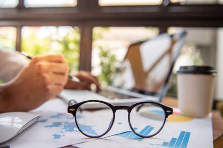 glasses and laptop on wooden desktop in modern office with accessories,Copy space for your textの写真素材