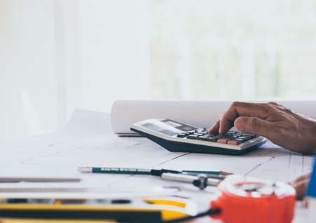 Close up man hand using calculator Calculating bonus(Or other compensation) to employees to increase productivity.Writing paper on desk.Selective Focusの写真素材
