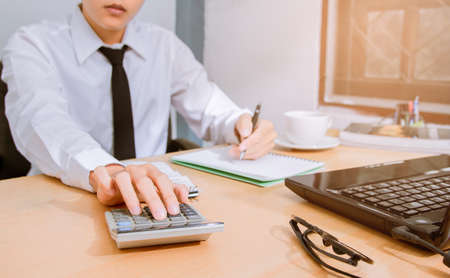 Asian businessman in white shirt and black tie, calculate the tax leading to the settlement liquidation.の写真素材