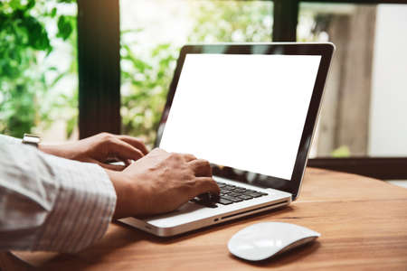 Business man  hands using laptop with blank screen on desk in cafe