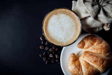 Latte art ,Croissant and Roasted coffee on black background in the morning