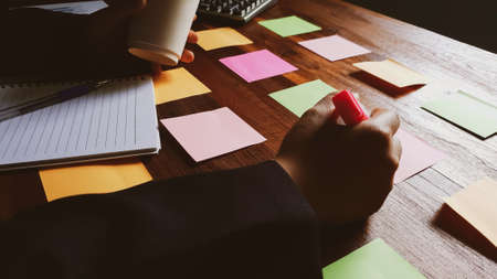 Start up. Business man in black suit meeting at home office and using notes  share design planning brainstorming idea on desktop wood table.の写真素材