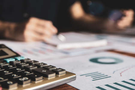 Close-up calculator,Asian young business man of student holding a pen writing letter on paper at homeの写真素材