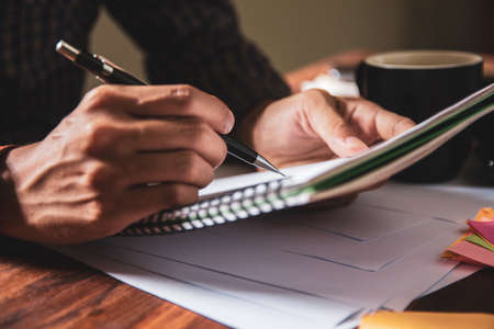 Asian young business man of student holding a pen writing letter on paper at home