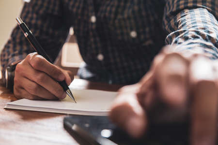 Asian young business man of student holding a pen writing letter on paper at homeの写真素材