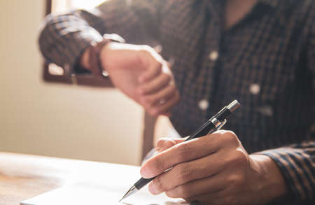 Look time, Asian young business man of student holding a pen writing letter on paper at homeの写真素材