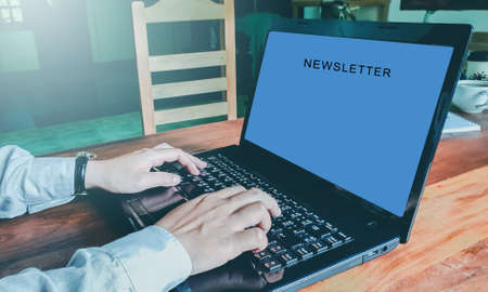 Newsletter concept Hand of businessman checking message box on digital laptop Vintage tone filter.Top viewの写真素材