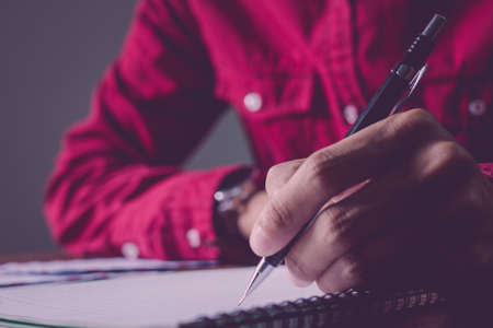 Asian young business man of student holding a pen writing letter on paper at home