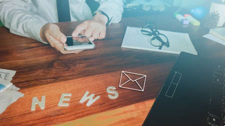 Newsletter concept Hand of businessman checking message box on digital mobile phone Vintage tone filter.Top viewの写真素材
