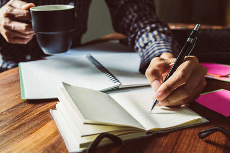 Asian young business man of student holding a pen writing letter on paper at home