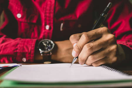 Asian young business man of student holding a pen writing letter on paper at homeの写真素材