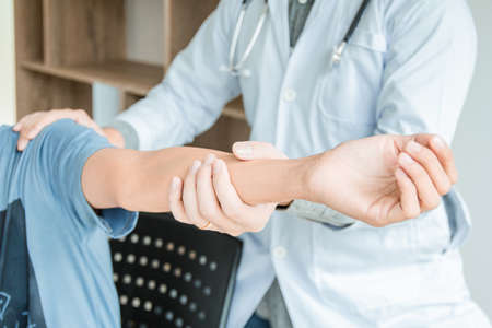 Concept healthy ,Male Patient in blue shirt visiting Doctor of Orthopedics examining injured arm of...
