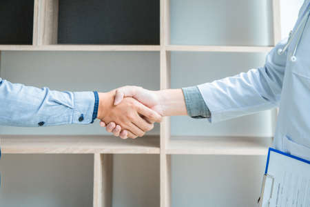 Doctor at the clinic giving a handshake to man patient, health care concept