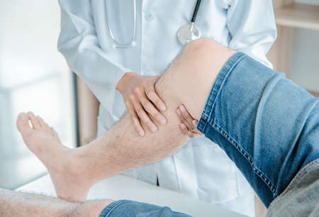 Concept healthy ,Male Patient in blue shirt visiting Doctor of Orthopedics examining injured leg and...