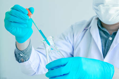 Medical science or male in laboratory room researcher performs tests of  dropper with blue liquid, Experimental Drug Treatment Chemicalsの写真素材