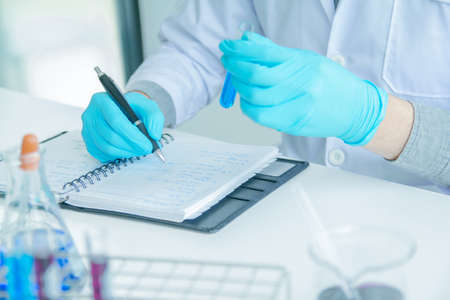Medical science or male Compiling an Analysis Report in laboratory room research performs tests with...