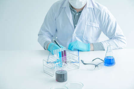 Medical science or male Compiling an Analysis Report in laboratory room research performs tests with blue liquid on test tube, Experimental Drug Treatment Chemicalsの写真素材