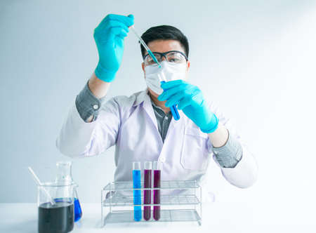 Medical science or male in laboratory room researcher performs tests of  dropper with blue liquid,...