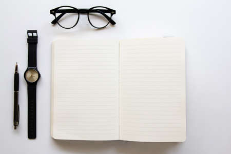 Top view. Black vintage glasses and open book and watch. Minimal Style on white background use for...