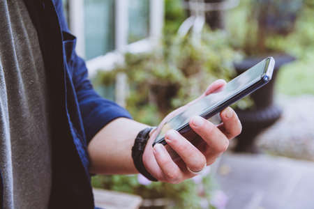Newsletter concept Hand of young man checking message box on digital mobile phone Vintage tone...