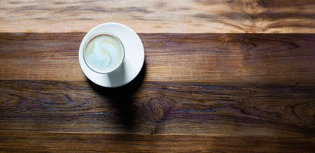 Top view,cup of hot coffee with foam and smoke on wooden table in the morning. copyspace for your textの写真素材