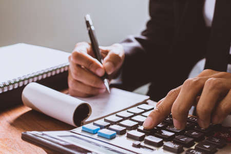 businessman hand using calculator Calculating bonus(Or other compensation) to employees to increase productivity.Writing paper on desk.Selective Focusの写真素材