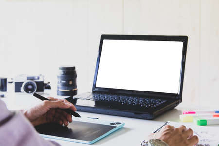 Designer in purple shirt, Graphic creative holding taplet computer and working on laptop in small  office Selective focus.の写真素材