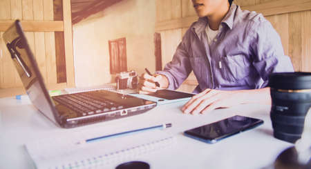 Designer of Graphic creative  holding Mouse pen and  working on laptop in office,Sunset background,Selective focus.の写真素材
