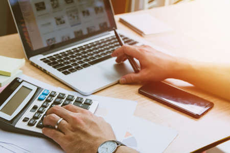 businessman hand using calculator Calculating bonus(Or other compensation) to employees to increase productivity. and using laptop Selective Focusの写真素材