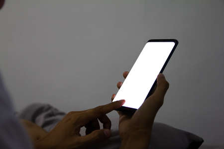 Young man sitting on the bed using smartphone at late night, Phone disease and Nomophobia. Healthy...