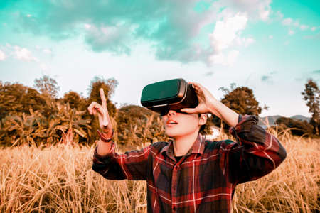 Asian man in gold rice field wearing glasses of glasses of virtual reality dissolving into pixels....