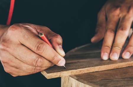 Close-up Man of Carpenter using pencil equipment drawing and plan design on wooden product. Small business Conceptの写真素材
