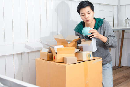 Young man surprised and unpacking the package received online shopping parcel opening boxes buying, is pig of saving moneyの写真素材