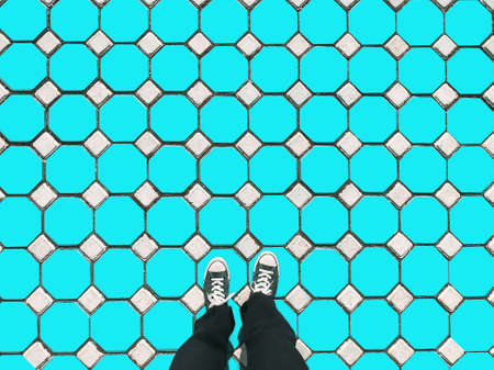 Man wearing old blue sneakers in blue trousers standing on hexagon floor fashion design concept, modern. pattern backgroundの写真素材