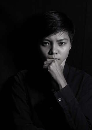 Studio portrait of a Thai Asian LGBT,women handsome beautiful young man  standing on black backdrop...
