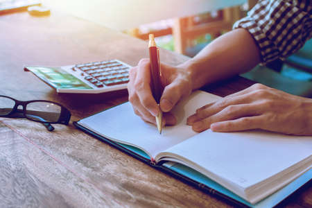 businessman Writing paper and using calculator Calculating bonus(Or other compensation) to employees...