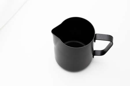 Black milk stainless pitcher object make coffee on white table and fabric backgroundの写真素材