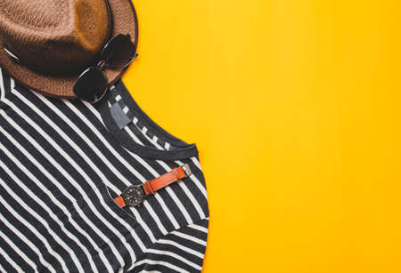 Top view. accessories clothes travel summer concept the beach with white black shirt sunglasses vintage watch, hat on yellow background.Copy space for your textの写真素材
