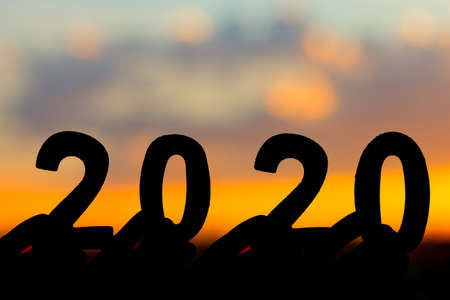 Silhouette 2020 Happy New Year of Hand holding wooden number on  sky and cloud twilight beautiful nature background.の写真素材