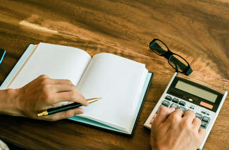businessman Writing paper and using calculator Calculating bonus(Or other compensation) to employees...