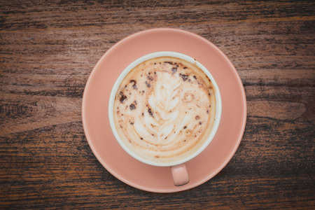Top view, Hot coffee latte art in cup on brown wooden table .Food drink conceptの写真素材