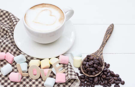 Coffee cup white hart latte art and dessert of marshmallow, Roasted coffee beans on white wooden.Copy space for you textの写真素材