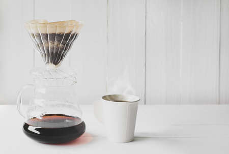 Dripping coffee and white paper cup on wood table background