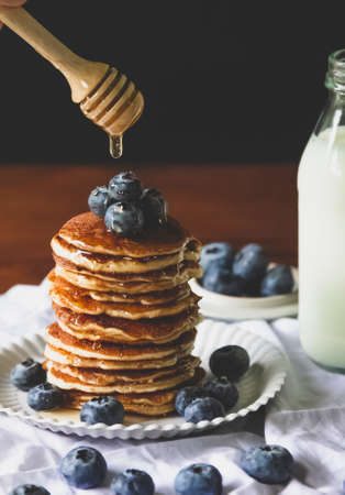 Blueberry pancake Homemade  and pouring   honey with milk  for a breakfast on wood table. Vertical...